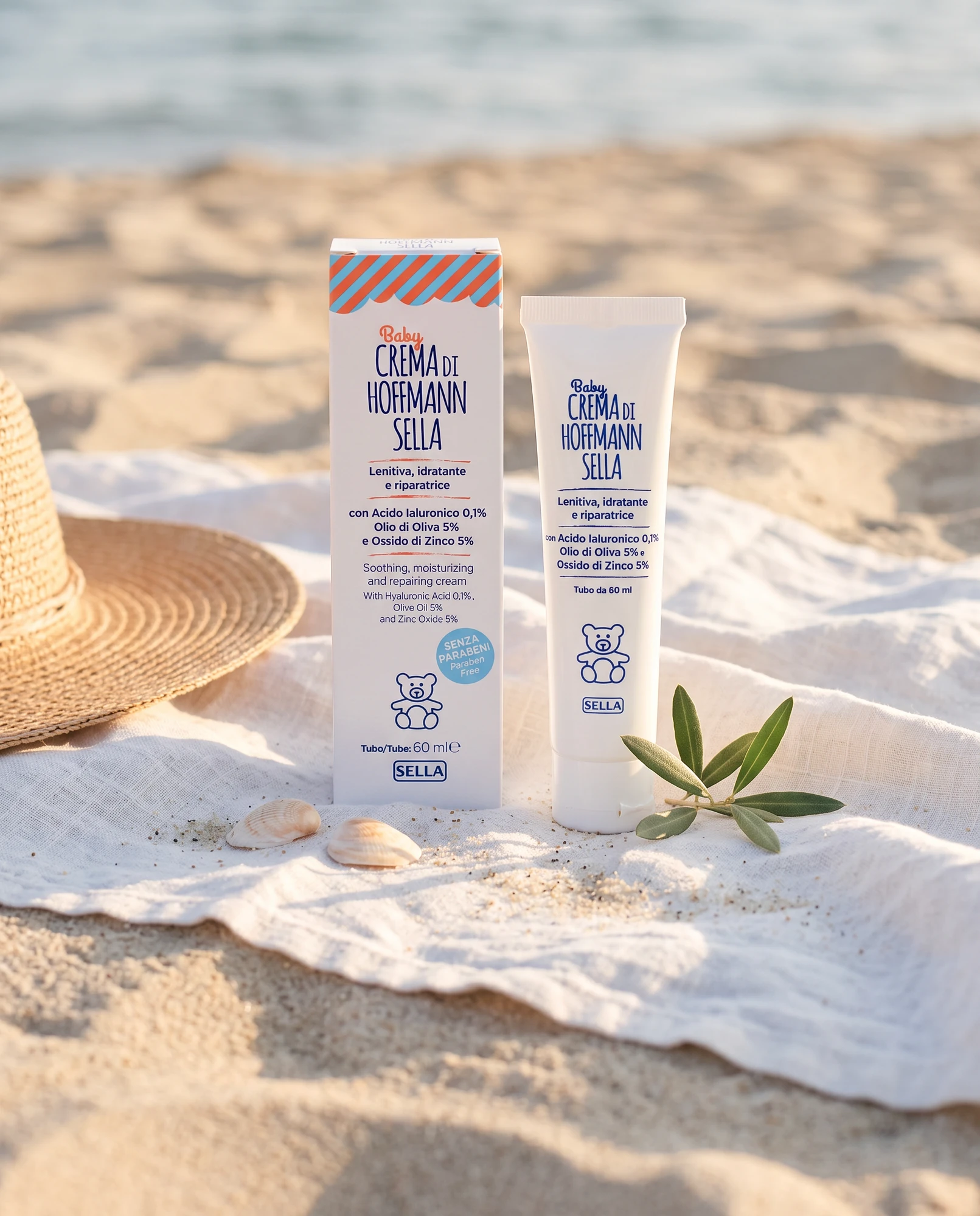 Tubo e confezione di Baby Crema di Hoffmann Sella su telo in spiaggia con cappello di paglia e conchiglie