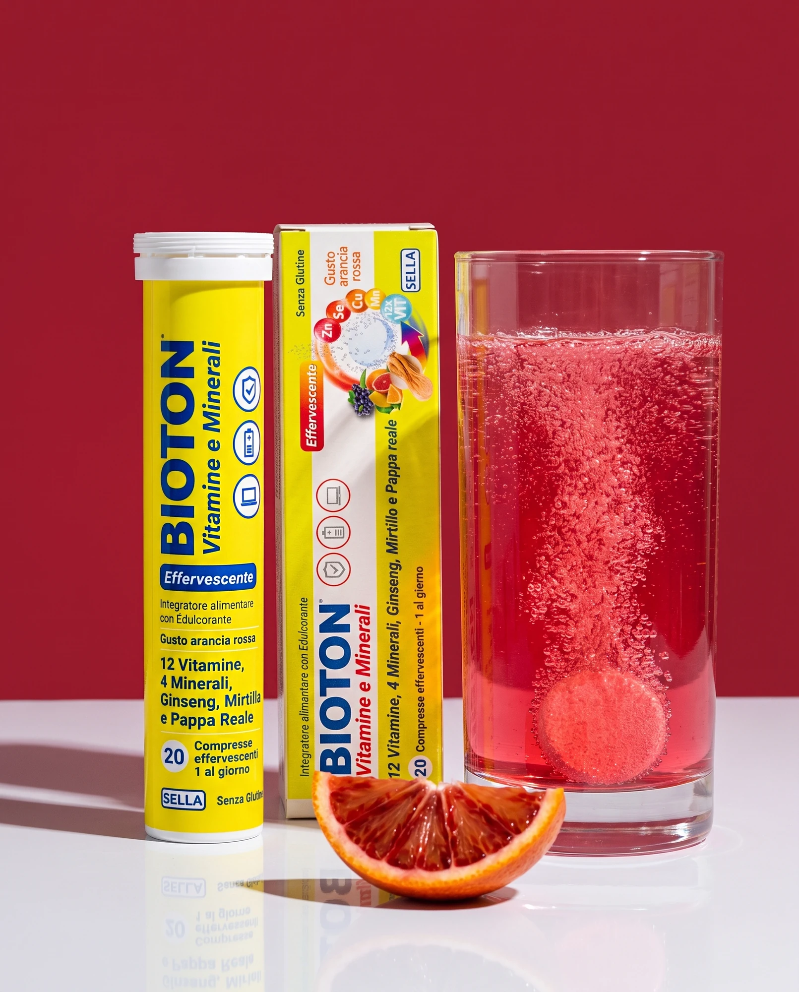 Tubo e confezione di Bioton Vitamine e Minerali effervescente con bicchiere di bevanda frizzante all'arancia rossa