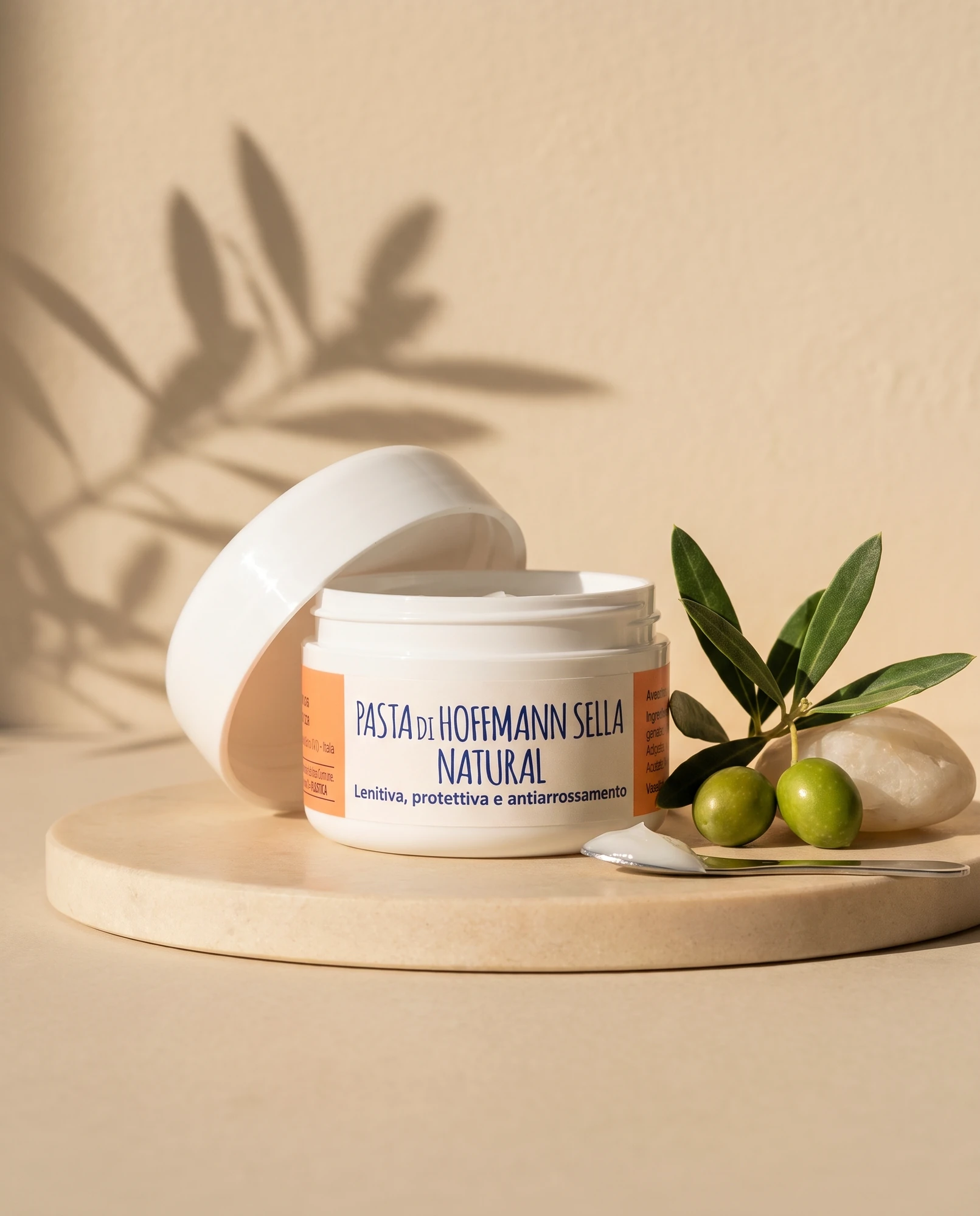 Vasetto aperto di Pasta di Hoffmann Sella Natural su vassoio di marmo con rametto d'ulivo e olive