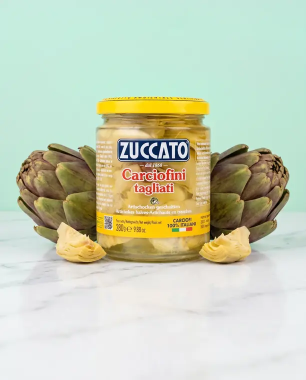 Vasetto di carciofini tagliati Zuccato tra due carciofi interi su fondo verde acqua